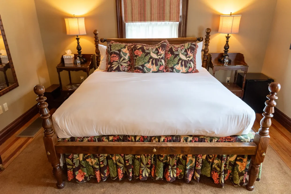 Cozy Stewart Room featuring a wooden bed with floral pillows, warm lighting, and elegant decor.